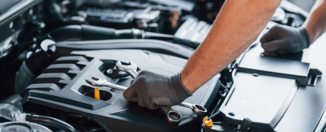 An otomotive specialist looking under the hood of a car