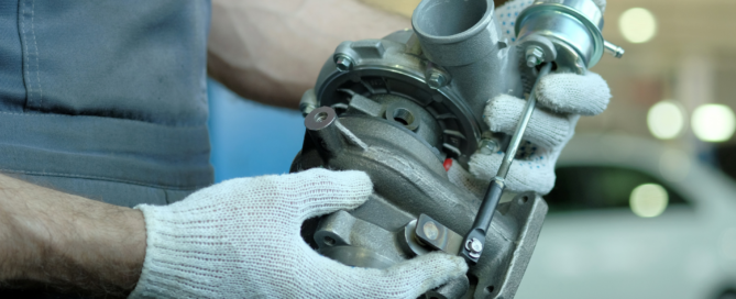 A mechanic holding a turbocharger in his hands