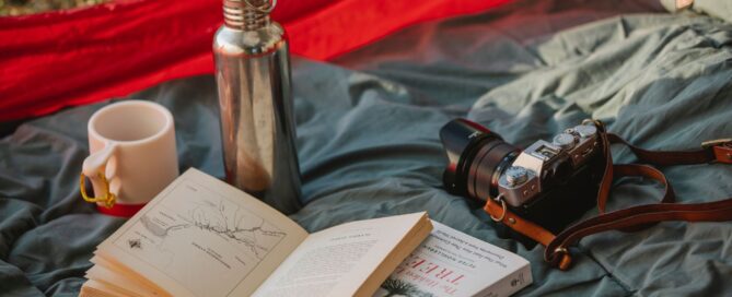 Gourde, mug, livres et caméra sur un sol de tente de camping